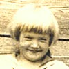 Alice Young with fish in front of the boathouse, about age five